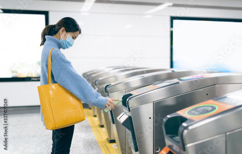 That young asian woman wearing a surgical mask using smart phone to pay at metro station.