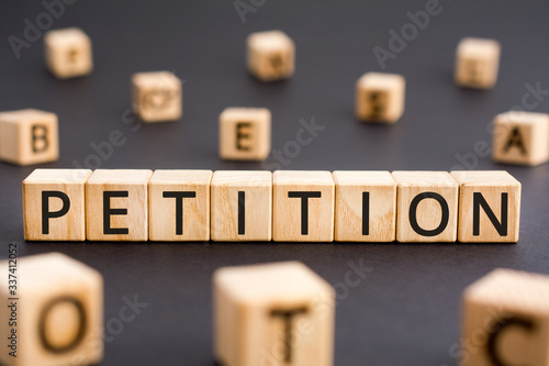 Petition - word from wooden blocks with letters, a formal request petition concept, random letters around black background photo