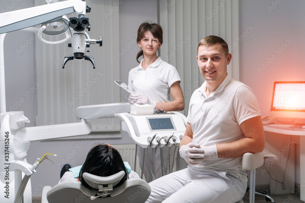 Fototapeta premium Professional dentist and nurse doing operation on female patient. A team of dentists with client in a dental office, oral care, healthy teeth, stomatology concept.