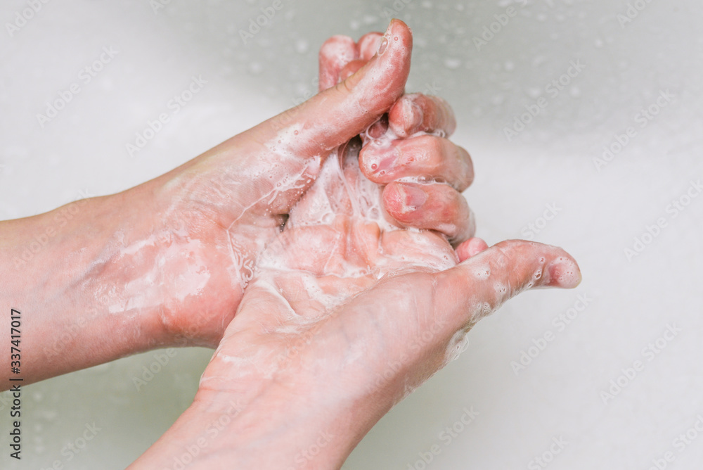 Woman uses soap and washes her hands under a faucet. Hygiene and hand cleaning. Prevention and control of coronavirus.