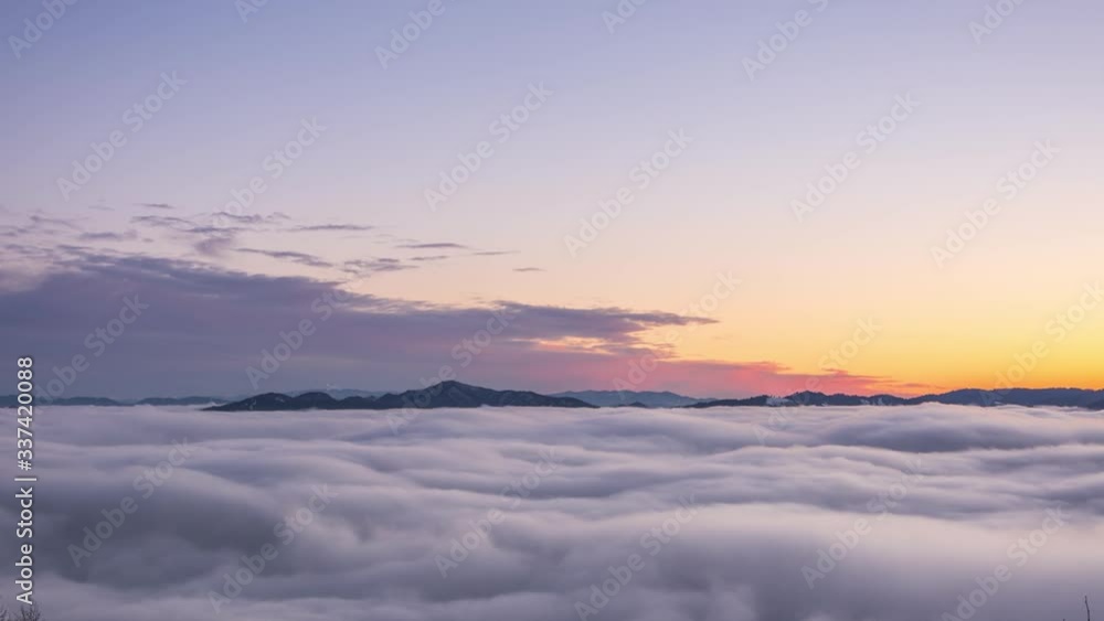 Time lapse zoom in colorful sea of clouds covering landscape with occasional hill and mountain peaking above the blanket of clouds Time lapse zoom in colorful sea of clouds covering landscape with occasional hill and mountain peaking above the blanket of clouds