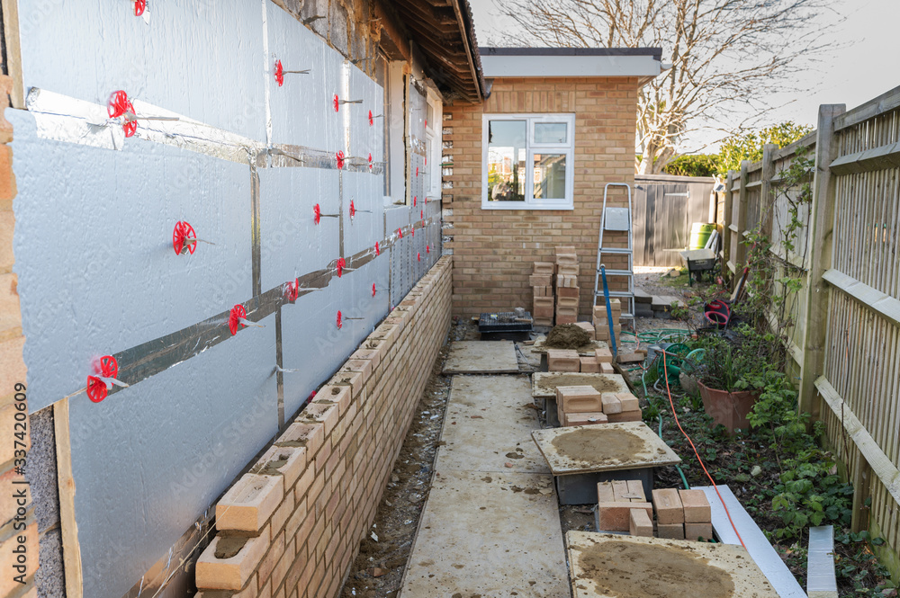 Bricklaying in residential property, renovation project, rows of bricks over insulation and block work, selective focus