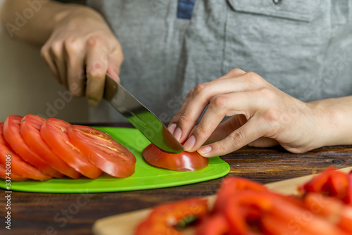 a man is slicing tomatoes and red onions on a green Board. vegetable vitamin salad