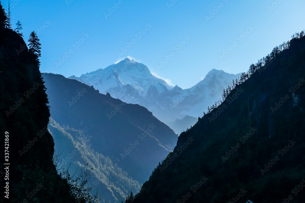 A close up view on snow caped Himalayan peak seen from Annapurna Circuit Trek, Nepal. Sharp and steep slopes of the mountain. First sunbeams reaching the snowy peak. Serenity an peace