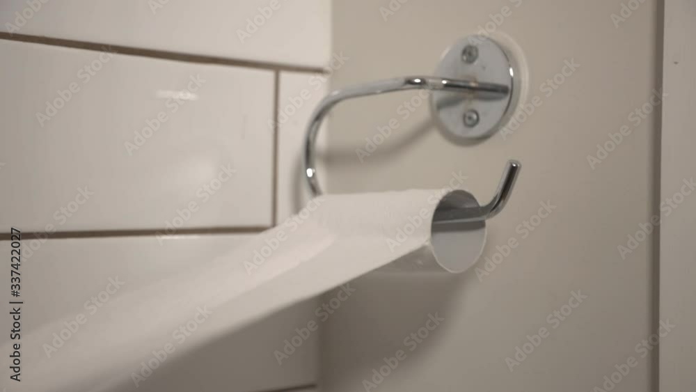 A Person Pulling The Last Pieces of A Toilet Paper On The Bathroom Wall - Closeup Shot A Person Pulling The Last Pieces of A Toilet Paper On The Bathroom Wall - Closeup Shot