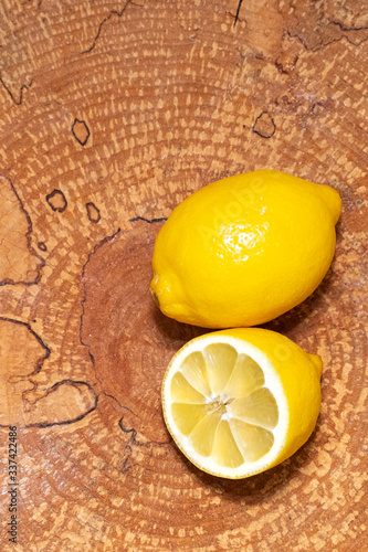 Yellow juicy, ripe lemon and half a lemon on a wooden background, top view. Copy space