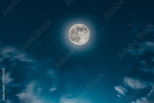 Magic blue night sky landscape with clouds and fullmoon and stars closeup.