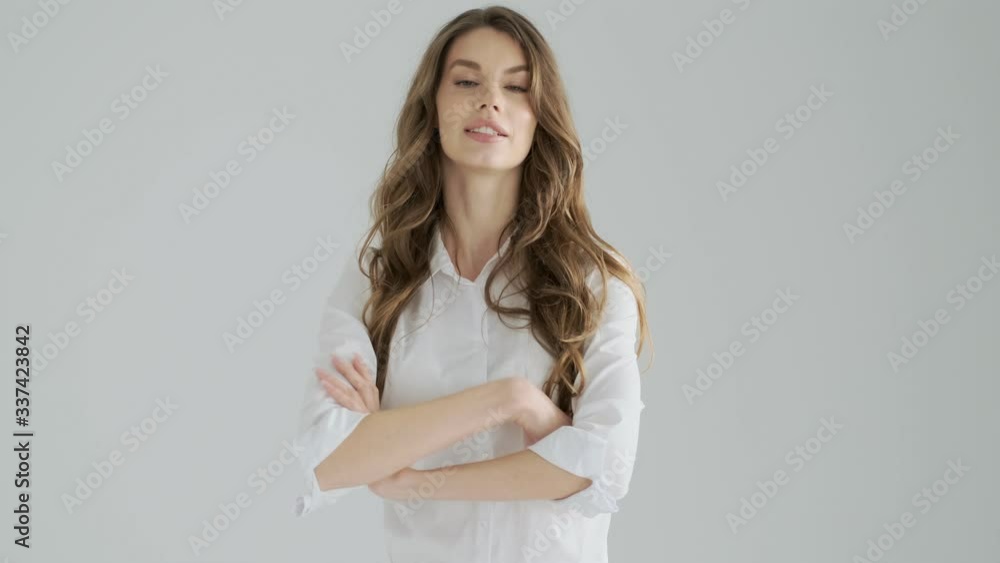 A beautiful confident young woman in office clothes is showing a thumb up gesture isolated over a gray background in studio A beautiful confident young woman in office clothes is showing a thumb up gesture isolated over a gray background in studio