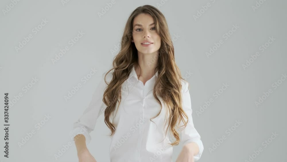 A beautiful young woman in office clothes is doing a confident pose while crossing her hands isolated over a gray background in studio A beautiful young woman in office clothes is doing a confident pose while crossing her hands isolated over a gray background in studio