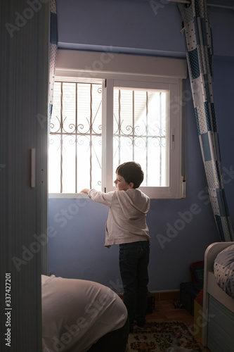  boy looks out the bedroom window while his mother orders the clothes