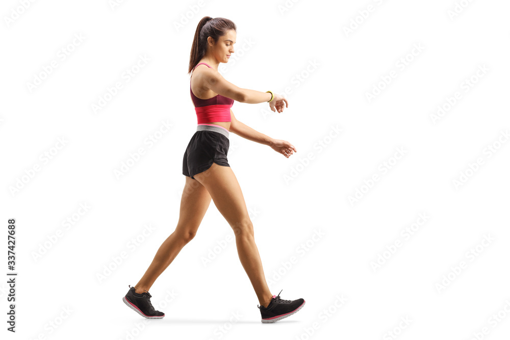 Fit young woman walking checking her sports arm-band