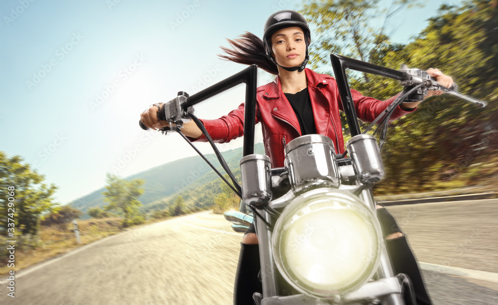 Young female biker riding a custom motorbike on road