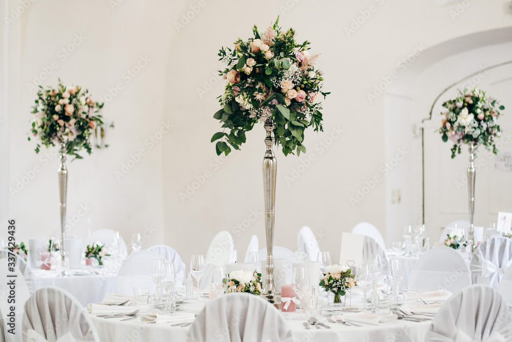 Fototapeta premium Tables for guests at the wedding, decorated with fresh flowers compositions, white tablecloth, candles, tableware