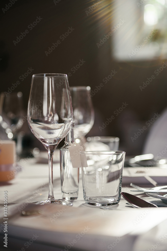 Closeup beautiful table decoration, with fresh peonies and greenery, pink candles, silver candlestick., wine glasses and plates