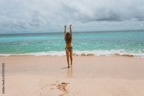 Beautiful and young girl in a swimsuit posing on the ocean and sea with blue waves. Woman in a swimsuit model and fashion posing. Relax and relaxation on the island of Bali