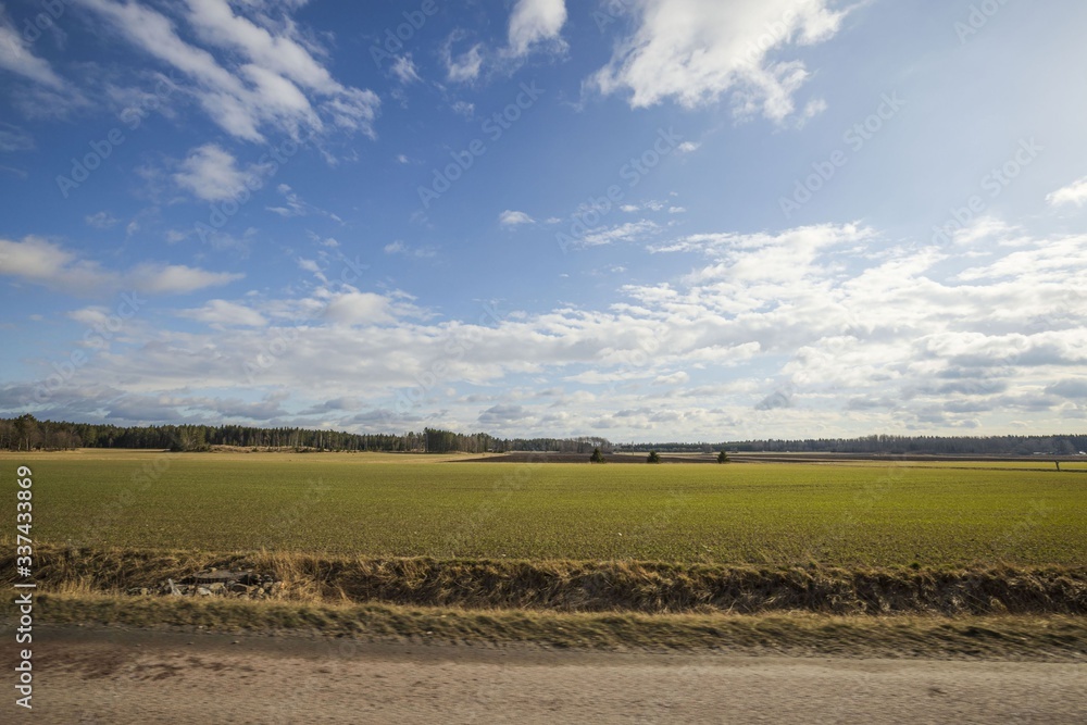 Beautiful landscape view with fields, forest trees and blue sky with white clouds. Gorgeous spring backgrounds. Sweden.
