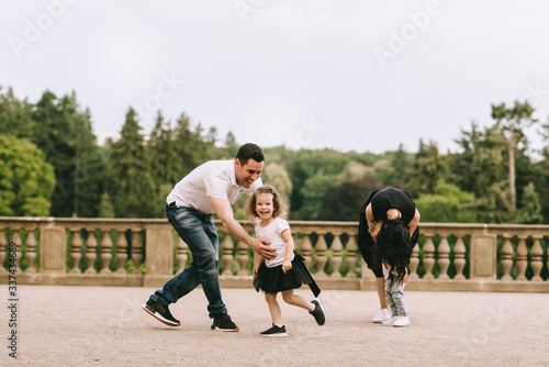 Fototapeta Naklejka Na Ścianę i Meble -  Handsome young father and beautiful mother in sunny summer nature playing with their cute small childrens