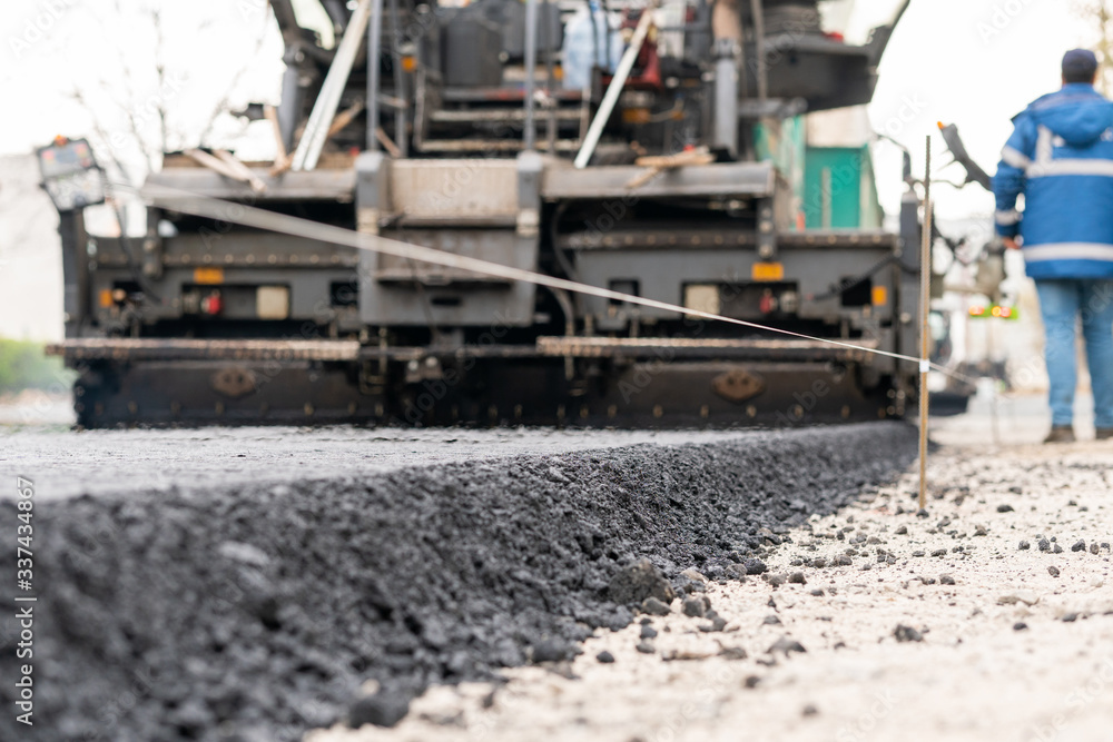 Paver machine is laying fresh asphalt on city road Paver machine is laying fresh asphalt on city road
