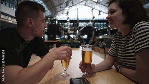 Young couple drinking bear and waiting for food in food market in Lisbon, Portugal