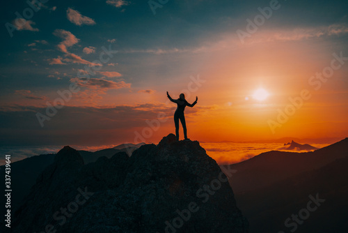 Girl on a cliff at sunset, silhouette