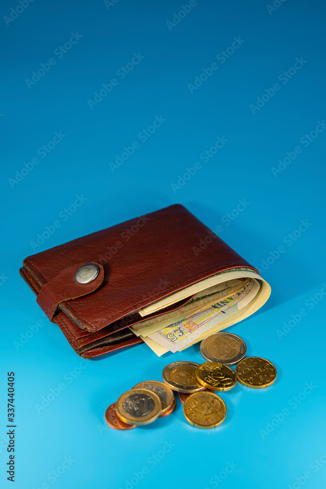 wallet with paper notes and euro cents and euro coins on a blue background. wallet with paper notes and euro cents and euro coins on a blue background.