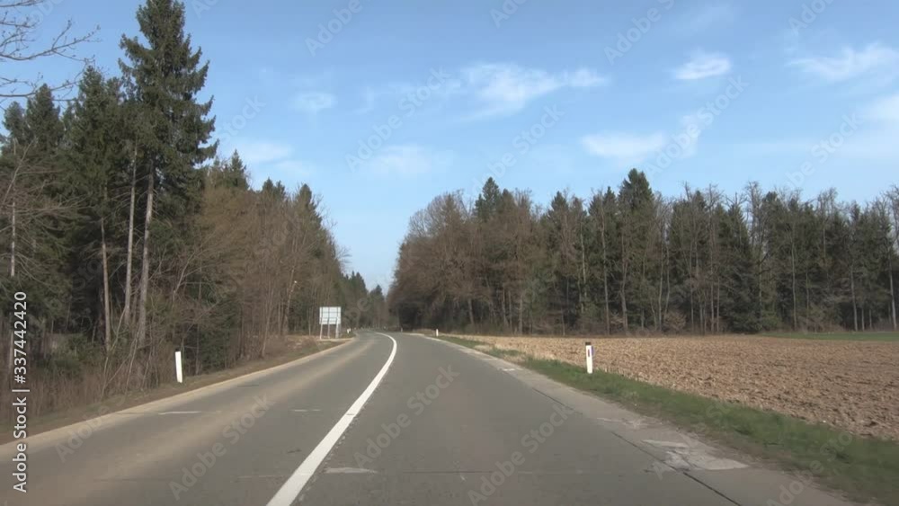Car dashboard POV driving on empty road in the countryside on a sunny day through a forest during coronavirus lockdown Car dashboard POV driving on empty road in the countryside on a sunny day through a forest during coronavirus lockdown
