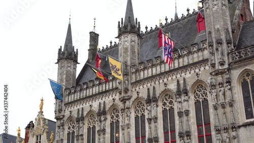 Low angle tilt down of Bruges City Hall, in the Market Square, on a windy day.  photo