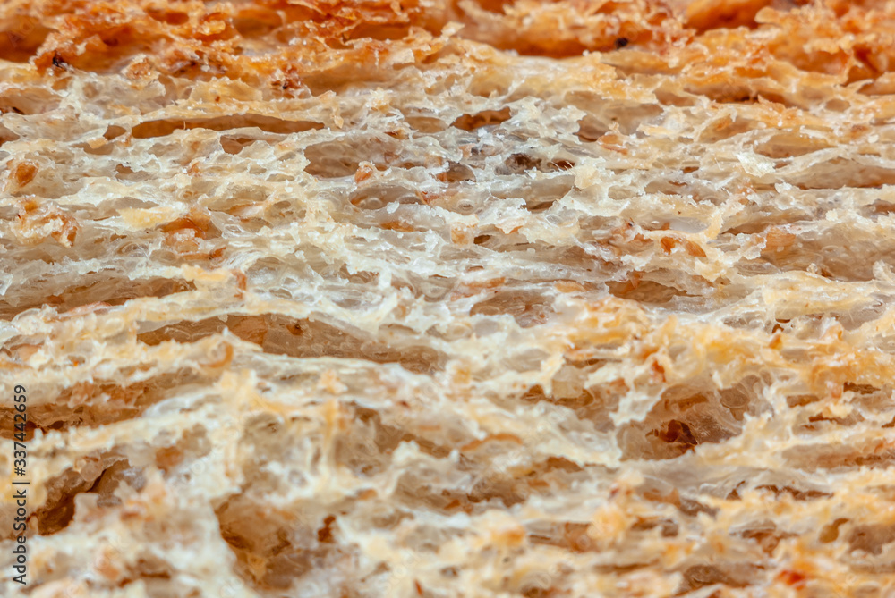 Macro photo of the texture of fresh wheat bread, a little toasted.
