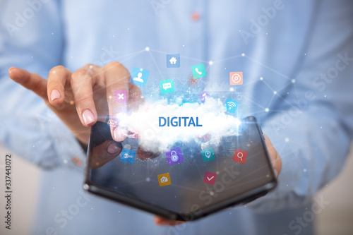 Fototapeta Naklejka Na Ścianę i Meble -  Businessman holding a foldable smartphone with DIGITAL inscription, technology concept