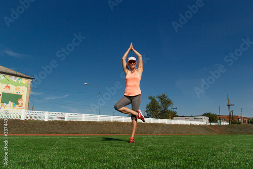 An elderly woman stands in a tree pose