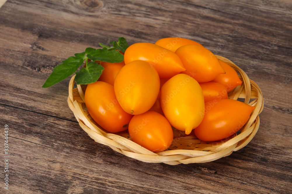 Yellow tomato heap in the wooden bowl Yellow tomato heap in the wooden bowl