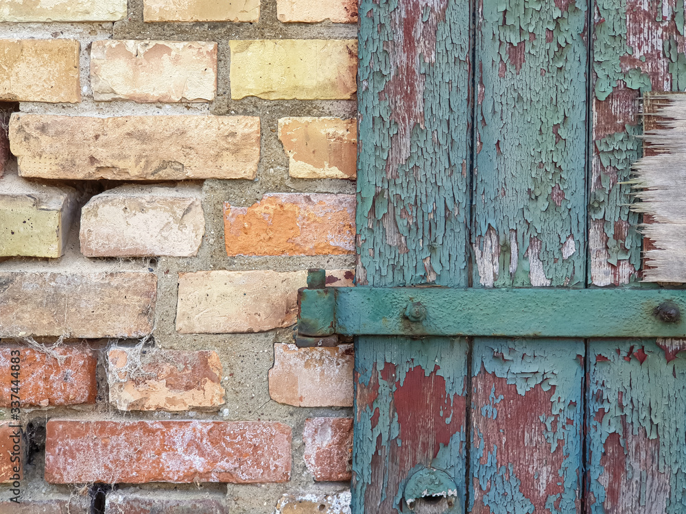 Background texture old door with green broken paint and a yellow brick wall Background texture old door with green broken paint and a yellow brick wall