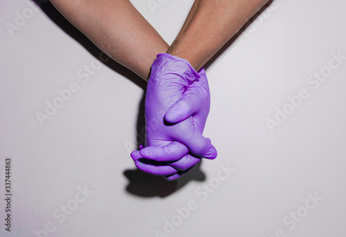 Doctors clasping hands with latex gloves as a sign of teamwork. Teamwork concept. Doctors saving lives concept. Flu, illness, pandemic and protection concept. Protection concept. 