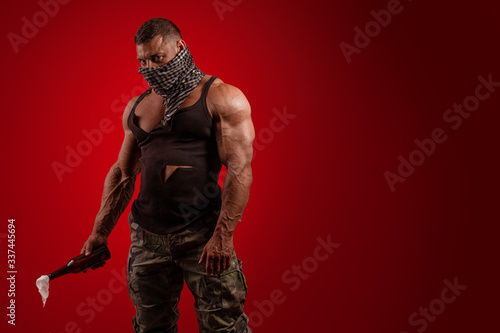 Young male athlete protester with a closed face with a Molotov cocktail in hands posing on a red background photo