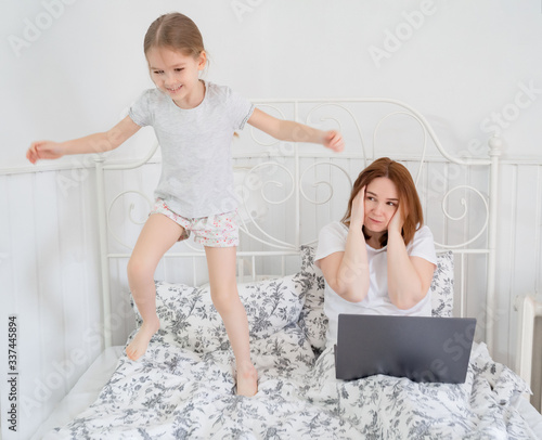 daughter interferes to work mom in bed. quarantine photo