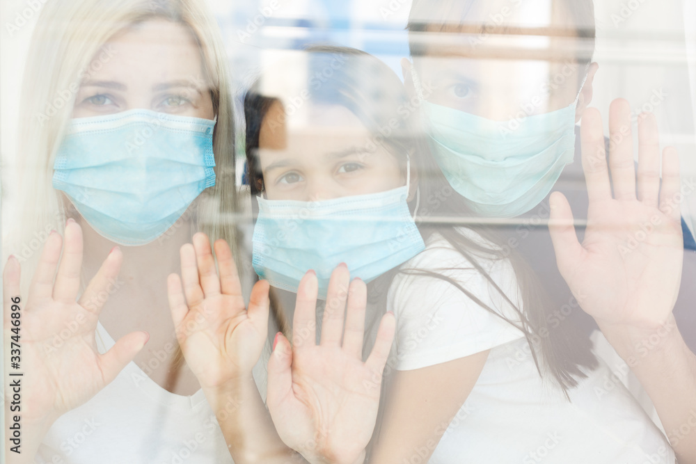 Family, standing behind the window, at home, quarantine due to coronavirus