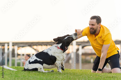 Handsome hipster man walking her dog and playing together. Friendship loving bond between owner and pet hunting dog. Funny expressive leisure time. Faithful friends of human. Companionship.