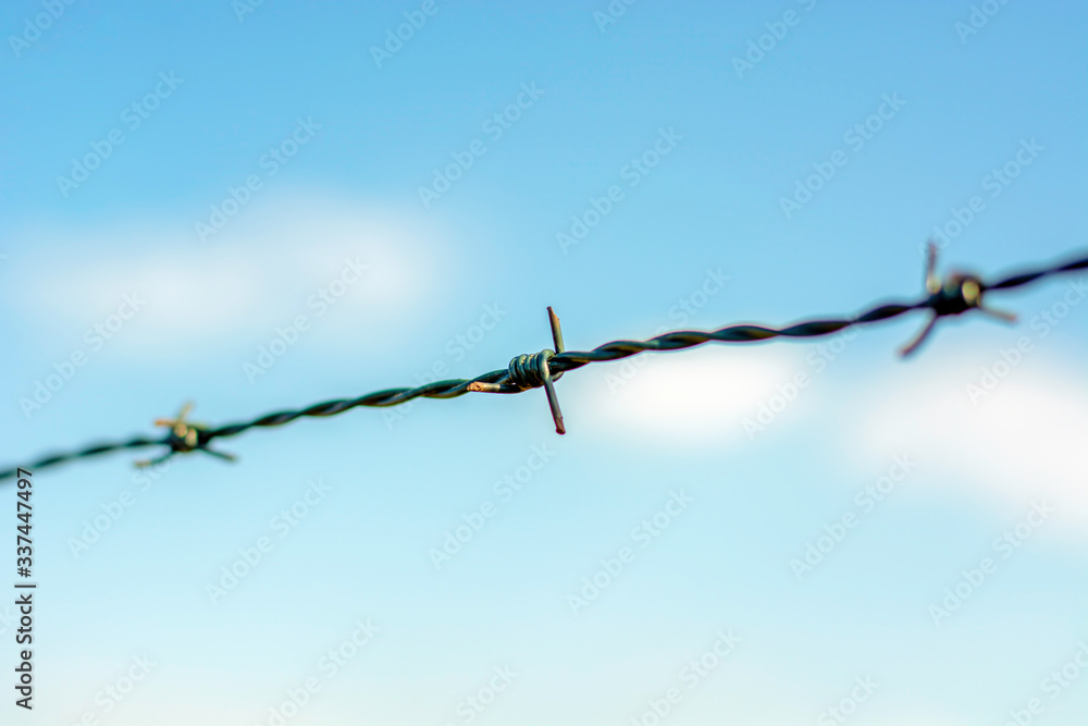 Close up barbed wire fence against blue sky. Close up barbed wire fence against blue sky.