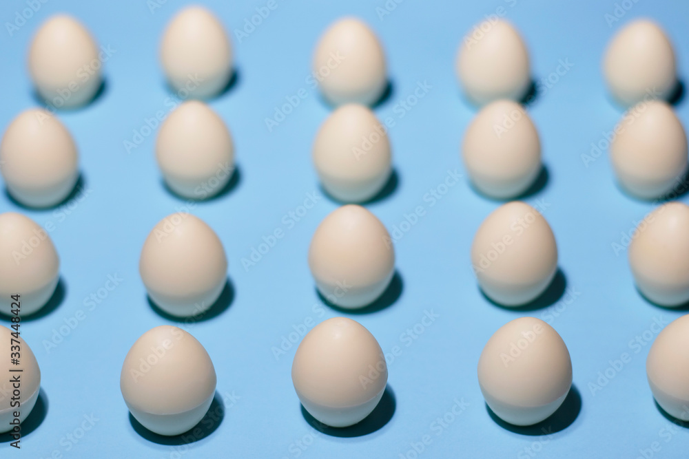 Pattern of white chocolate eggs on a pale blue. The parallel lines of chocolate eggs are shot close. Delicate photo specially for your Easter design and any other creative design. Pattern of white chocolate eggs on a pale blue. The parallel lines of chocolate eggs are shot close. Delicate photo specially for your Easter design and any other creative design.