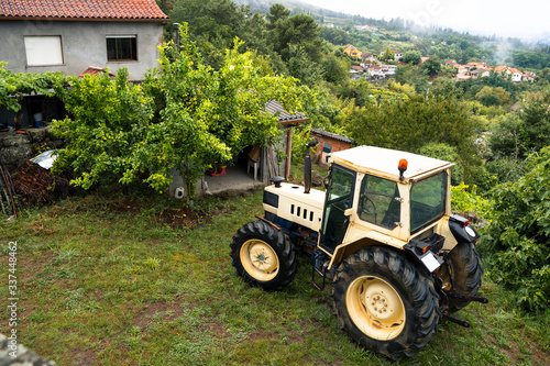 Horizontal top view of countryside tractor in the north of Spain  Galicia. Winter seasonal time. Humidity and rainy weather inside home. Nature rural landscape on green field with rustic houses.