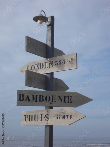 Schilderij op canvas Wooden pool with lampoon top with Dutch direction signs to LONDEN, BAMBOENIE, THUIS
