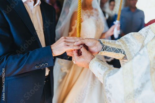 The priest holds a wedding ceremony in the church, rites and puts gold rings on the fingers of the newlyweds. Photography, concept.