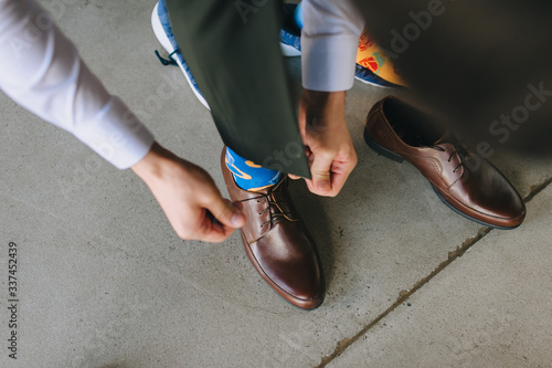 A man, the groom puts on brown leather shoes and ties the laces close-up. Morning businessman. Photography, concept.