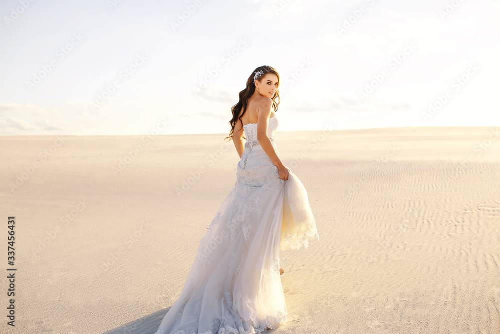 beautiful bride in a beautiful long dress walks on the sand in the desert, backlight, sunset, tender girl, designer wedding dress, a sense of freedom, the wind moves hair, desert dunes beautiful bride in a beautiful long dress walks on the sand in the desert, backlight, sunset, tender girl, designer wedding dress, a sense of freedom, the wind moves hair, desert dunes