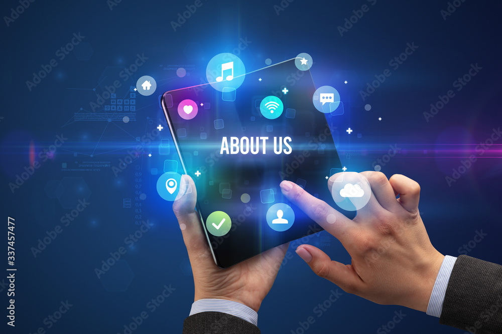 Businessman holding a foldable smartphone with ABOUT US inscription, social media concept Businessman holding a foldable smartphone with ABOUT US inscription, social media concept