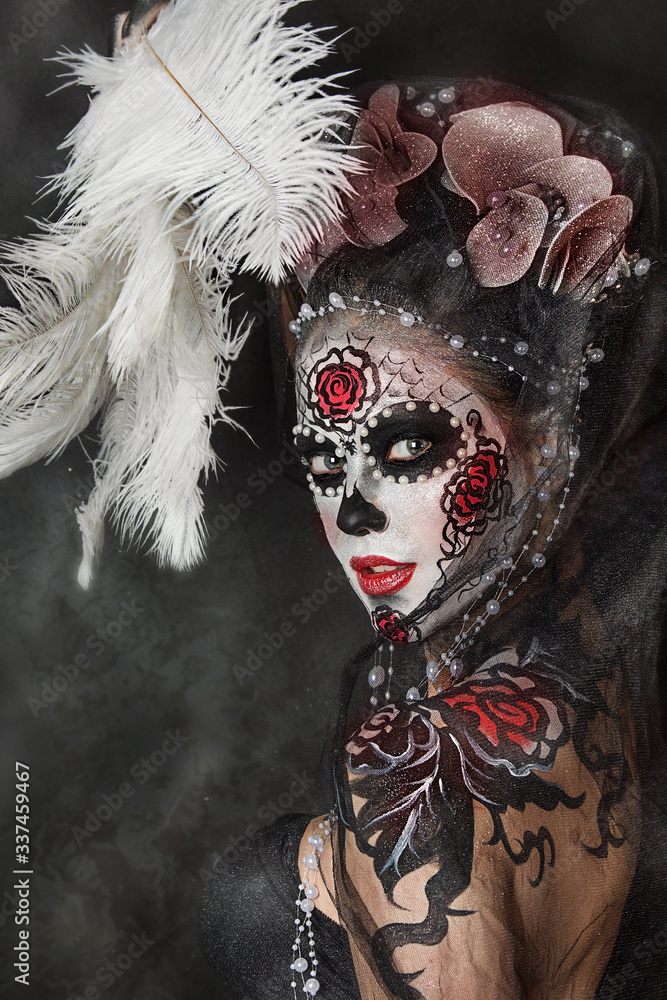 close up portrait of young beautiful girl with professional Halloween makeup. Mexican death. Big feathers on crown
