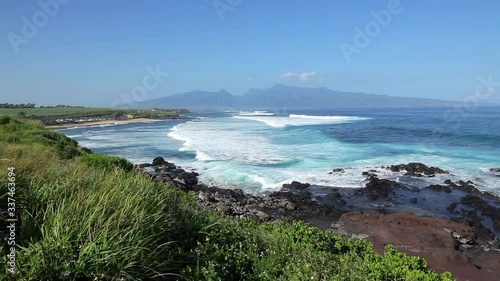 Ho'okipa State Park on Maui with large white waves rolling to shore with the West Maui Mountains and blue sky in the background on a sunny Hawaii day. photo