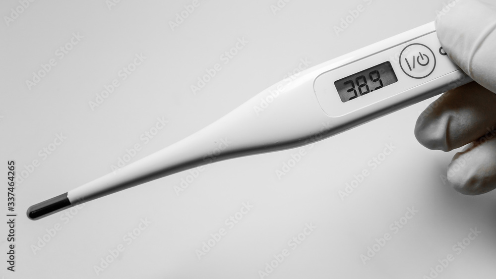 custom made wallpaper toronto digitalhands holding white digital thermometer on white background. Showed 38.9 c’. Fever and healthcare concept. Cover-19 test. healthcare concept