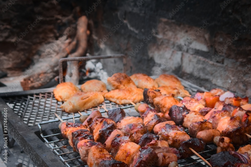 Pieces of meat, vegetable skewers and empanadas on the grill at a typical argentinian barbecue.