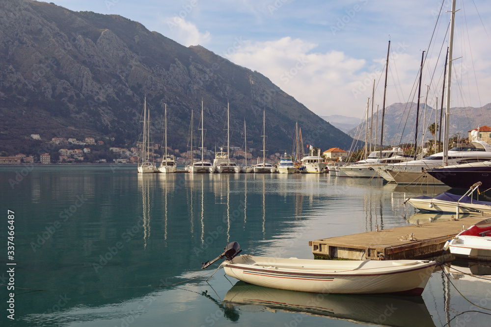 Port in Kotor city. Yachts and fishing boats on water on winter day. Montenegro, Adriatic Sea, Kotor Bay
